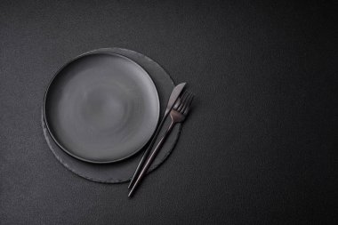 Empty black plate over dark stone background with copy space. Top view clipart