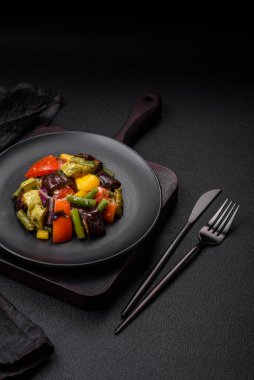 Lezzetli taze salata fırında patlıcan, domates, kabak, soğan, baharat ve koyu beton arka planda tuz.