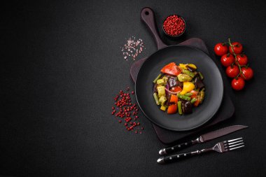 Lezzetli taze salata fırında patlıcan, domates, kabak, soğan, baharat ve koyu beton arka planda tuz.