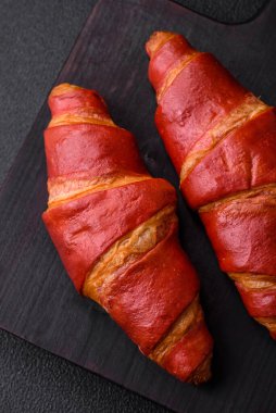 Lezzetli, çıtır çıtır, kırmızı kruvasan kremalı koyu desenli beton arka plan.