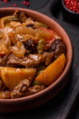 Lezzetli taze patates güveci, domates, soğan, havuç ve tuzlu et, baharat ve çimento arka planda bulunan otlar.