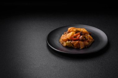 Lezzetli taze patates güveci, domates, soğan, havuç ve tuzlu et, baharat ve çimento arka planda bulunan otlar.