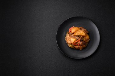 Lezzetli taze patates güveci, domates, soğan, havuç ve tuzlu et, baharat ve çimento arka planda bulunan otlar.