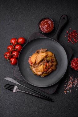 Lezzetli taze patates güveci, domates, soğan, havuç ve tuzlu et, baharat ve çimento arka planda bulunan otlar.