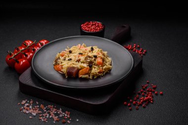 Koyu beton arka planda tavuk, havuç, böğürtlen, baharat ve bitkilerle nefis Özbek pilavı