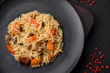 Koyu beton arka planda tavuk, havuç, böğürtlen, baharat ve bitkilerle nefis Özbek pilavı