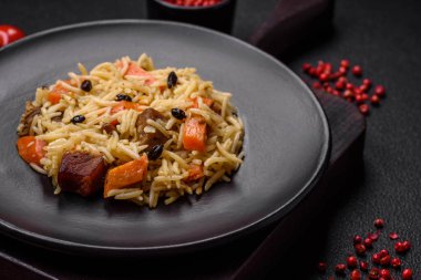 Koyu beton arka planda tavuk, havuç, böğürtlen, baharat ve bitkilerle nefis Özbek pilavı