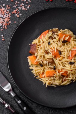 Koyu beton arka planda tavuk, havuç, böğürtlen, baharat ve bitkilerle nefis Özbek pilavı