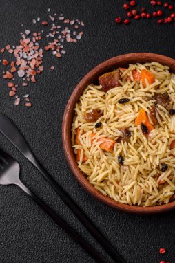 Koyu beton arka planda tavuk, havuç, böğürtlen, baharat ve bitkilerle nefis Özbek pilavı