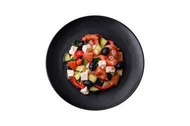 Siyah seramik tabakta zeytinli, domatesli, salatalıklı, peynirli, baharatlı, otlu ve zeytinyağlı taze Yunan salatası.