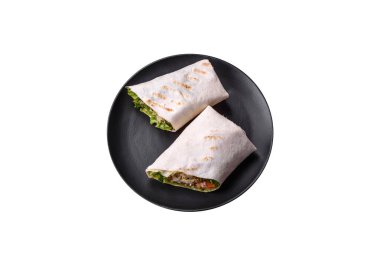 Delicious fresh roll with chicken, tomatoes, lettuce and cucumber in pita bread on a dark concrete background