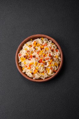 Lezzetli taze Asya erişteleri, sebze parçaları, et, tuz, baharat ve otlarla birlikte koyu beton bir arka planda.