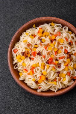 Lezzetli taze Asya erişteleri, sebze parçaları, et, tuz, baharat ve otlarla birlikte koyu beton bir arka planda.