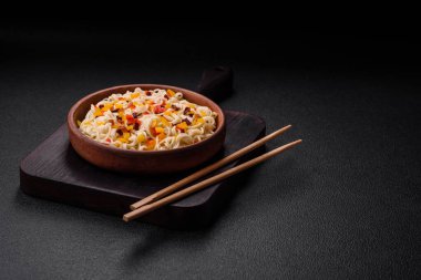 Lezzetli taze Asya erişteleri, sebze parçaları, et, tuz, baharat ve otlarla birlikte koyu beton bir arka planda.