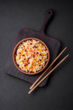 Lezzetli taze Asya erişteleri, sebze parçaları, et, tuz, baharat ve otlarla birlikte koyu beton bir arka planda.