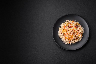 Lezzetli taze Asya erişteleri, sebze parçaları, et, tuz, baharat ve otlarla birlikte koyu beton bir arka planda.