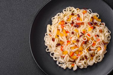 Lezzetli taze Asya erişteleri, sebze parçaları, et, tuz, baharat ve otlarla birlikte koyu beton bir arka planda.