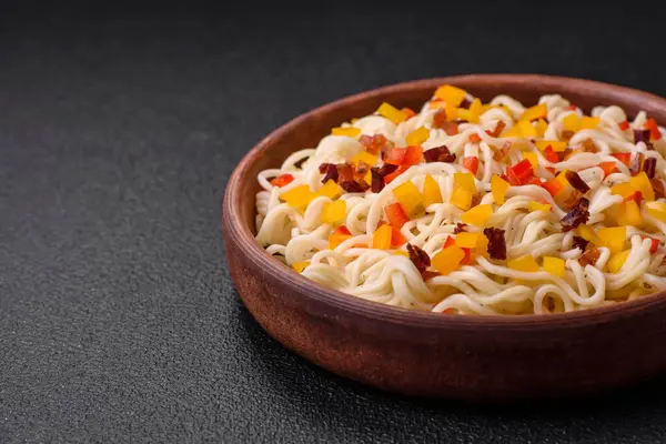 Lezzetli taze Asya erişteleri, sebze parçaları, et, tuz, baharat ve otlarla birlikte koyu beton bir arka planda.