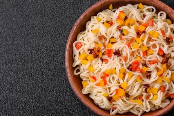 Lezzetli taze Asya erişteleri, sebze parçaları, et, tuz, baharat ve otlarla birlikte koyu beton bir arka planda.