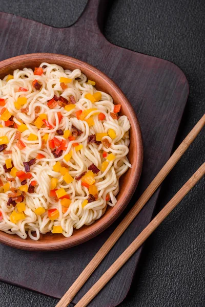 Lezzetli taze Asya erişteleri, sebze parçaları, et, tuz, baharat ve otlarla birlikte koyu beton bir arka planda.