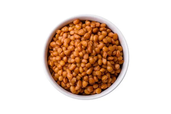 濃いコンクリートの背景にセラミックリブの白いボウルにおいしい健康的な缶詰のレンズ豆 — ストック写真