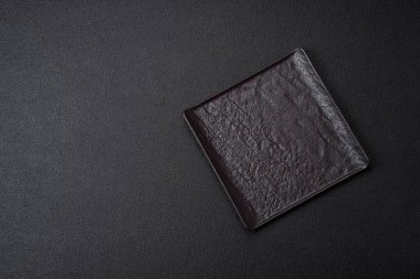 Koyu beton zemin üzerinde boş siyah kare seramik plaka. Asya yemeği pişirmek