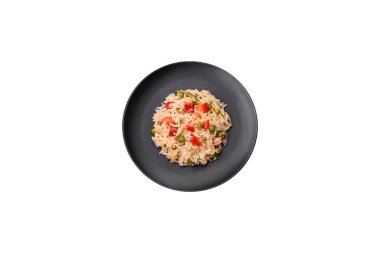 Lezzetli haşlanmış pirinç, sebzeli biber, bezelye ve kuşkonmaz fasulyesi, baharat ve otlu koyu beton arka planda.