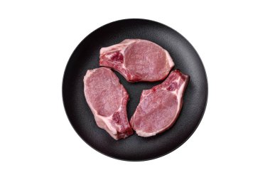 Kemikte çiğ domuz eti ya da tuz, baharat ve otlarla dilimlenmiş koyu beton arka planda kesilmiş kaburga.