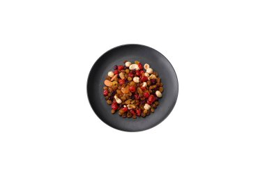 Kavrulmuş kaju, fındık ve ceviz karışımı, koyu beton arka planda kurutulmuş kızılcık ve kuru üzümler.