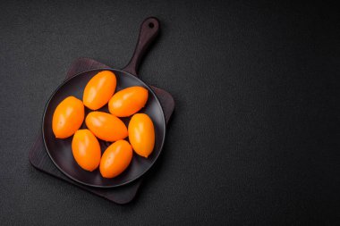 Siyah desenli çimento arka planda parlak, taze, sarı erik şekilli domatesler.