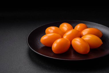 Siyah desenli çimento arka planda parlak, taze, sarı erik şekilli domatesler.