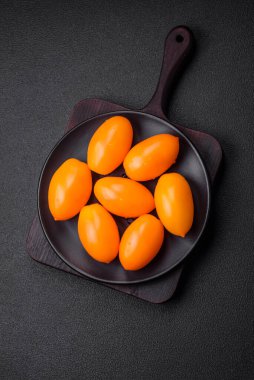 Siyah desenli çimento arka planda parlak, taze, sarı erik şekilli domatesler.