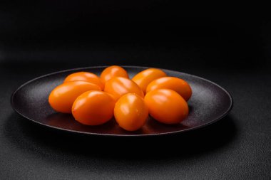 Siyah desenli çimento arka planda parlak, taze, sarı erik şekilli domatesler.