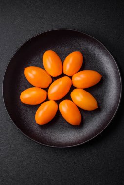 Siyah desenli çimento arka planda parlak, taze, sarı erik şekilli domatesler.