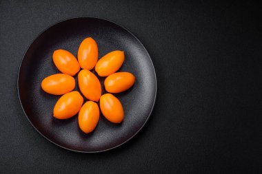 Siyah desenli çimento arka planda parlak, taze, sarı erik şekilli domatesler.