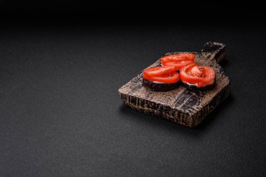 Daireler halinde kesilmiş lezzetli patlıcan ızgara ve mayonez ve domatesle pişirilmiş koyu beton arka planda.