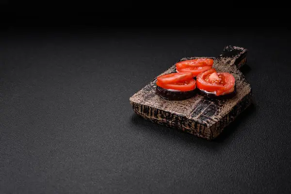 Daireler halinde kesilmiş lezzetli patlıcan ızgara ve mayonez ve domatesle pişirilmiş koyu beton arka planda.