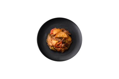 Lezzetli taze patates güveci, domates, soğan, havuç ve tuzlu et, baharat ve çimento arka planda bulunan otlar.