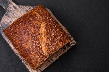 Koyu beton arka planda tahıl ve çekirdekli lezzetli çıtır kahverengi ekmek.