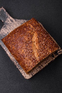 Koyu beton arka planda tahıl ve çekirdekli lezzetli çıtır kahverengi ekmek.