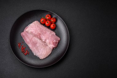 Koyu beton arka planda tuz, baharat ve otlarla sulu taze çiğ domuz eti.