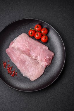 Koyu beton arka planda tuz, baharat ve otlarla sulu taze çiğ domuz eti.