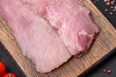 Koyu beton arka planda tuz, baharat ve otlarla sulu taze çiğ domuz eti.