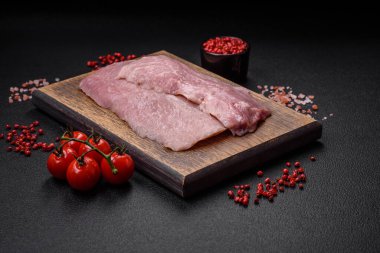 Koyu beton arka planda tuz, baharat ve otlarla sulu taze çiğ domuz eti.