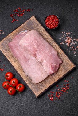 Koyu beton arka planda tuz, baharat ve otlarla sulu taze çiğ domuz eti.