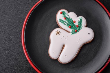 Seramik tabaklar, zencefilli çörekler ve koyu beton arkaplanda yeni yıl süslemelerinin diğer unsurlarından oluşan güzel bir Noel kompozisyonu