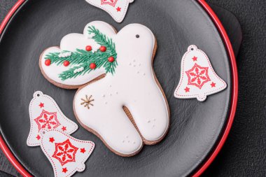 Seramik tabaklar, zencefilli çörekler ve koyu beton arkaplanda yeni yıl süslemelerinin diğer unsurlarından oluşan güzel bir Noel kompozisyonu