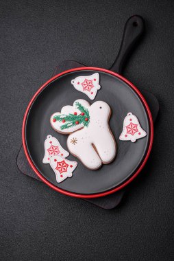 Seramik tabaklar, zencefilli çörekler ve koyu beton arkaplanda yeni yıl süslemelerinin diğer unsurlarından oluşan güzel bir Noel kompozisyonu