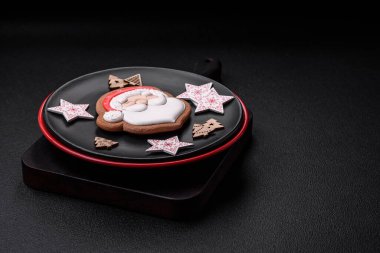 Seramik tabaklar, zencefilli çörekler ve koyu beton arkaplanda yeni yıl süslemelerinin diğer unsurlarından oluşan güzel bir Noel kompozisyonu