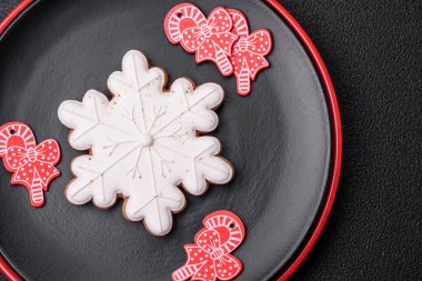 Seramik tabaklar, zencefilli çörekler ve koyu beton arkaplanda yeni yıl süslemelerinin diğer unsurlarından oluşan güzel bir Noel kompozisyonu